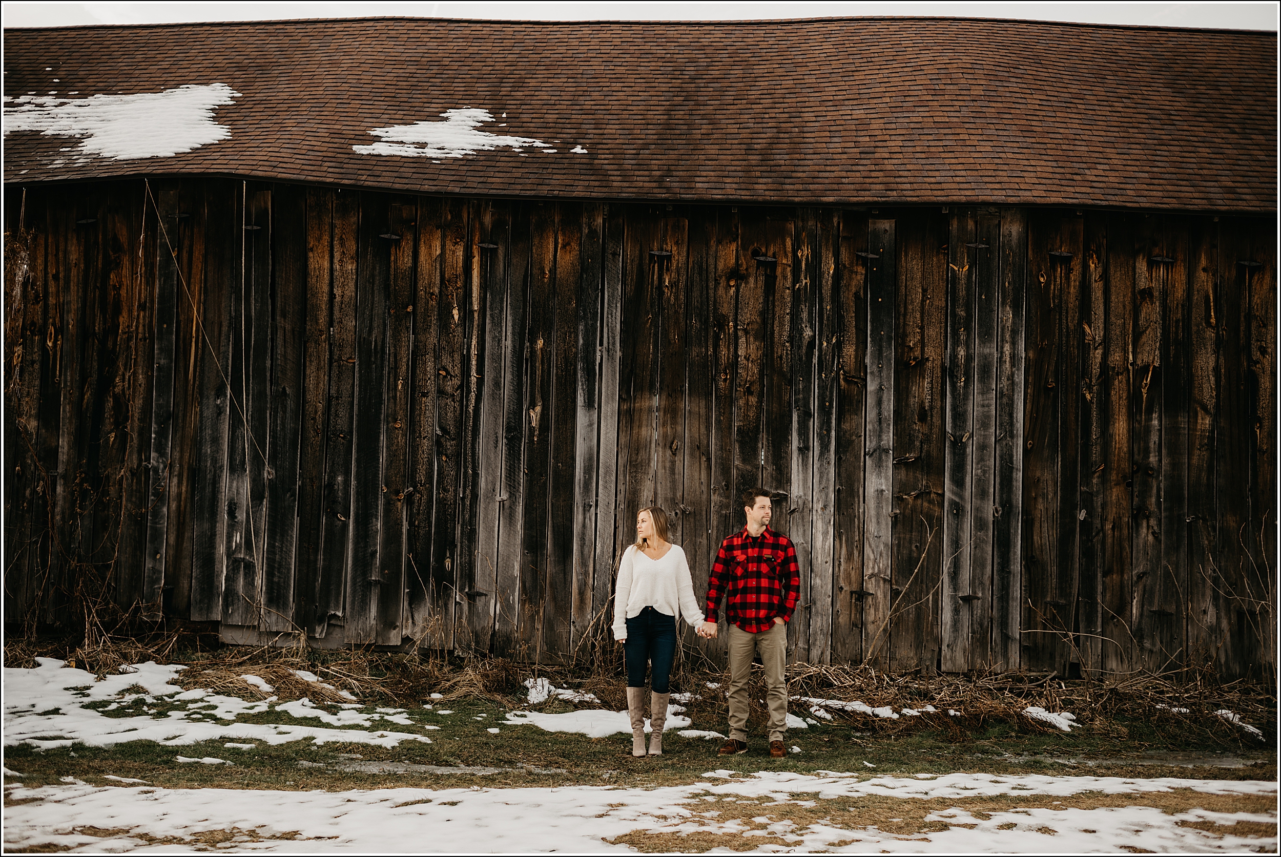 engagement rustic holding hands looking away in front of old brown barn